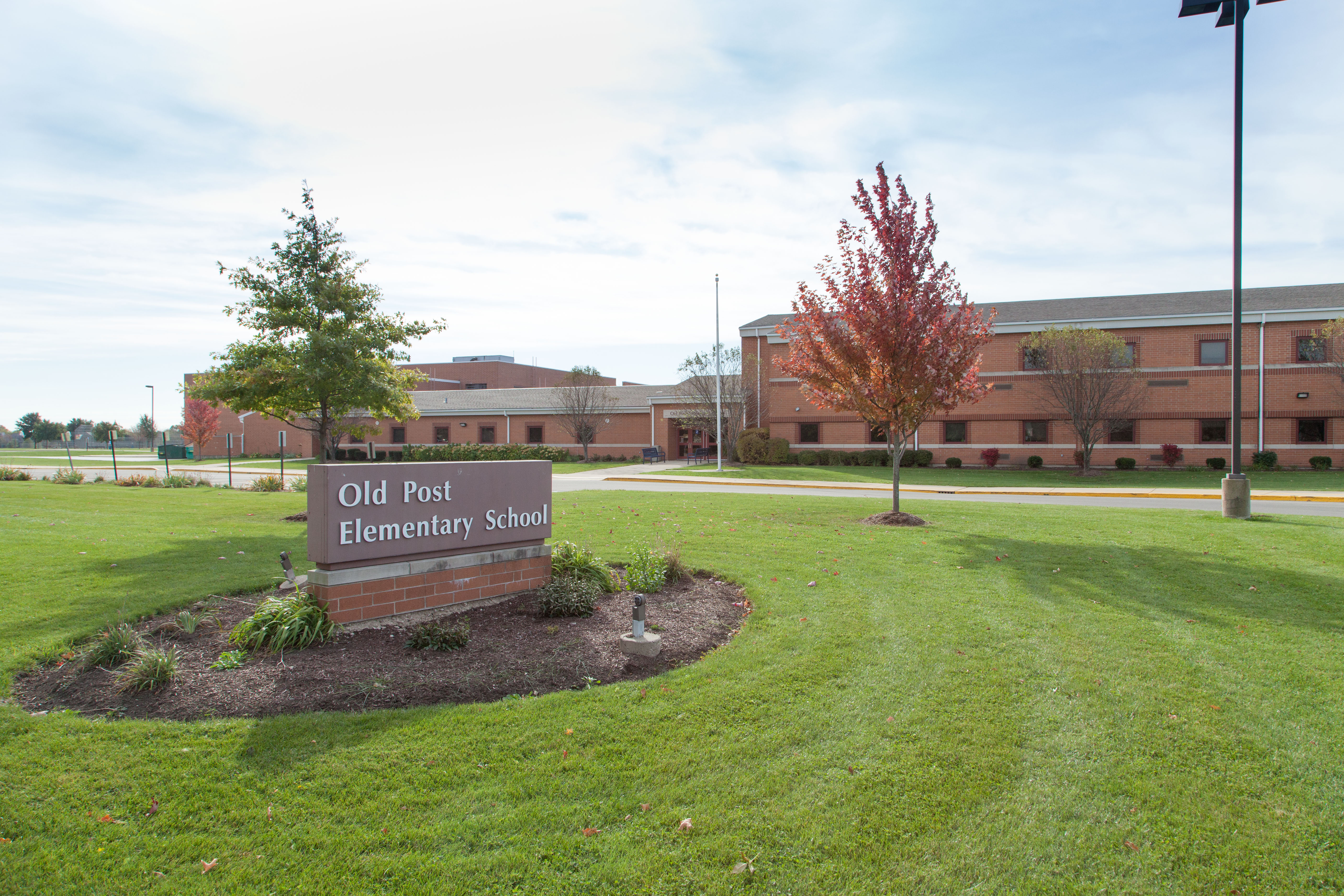 Front of Old Post Elementary School highlighting the main sign and entrance way with a bright blue sky in the background. 